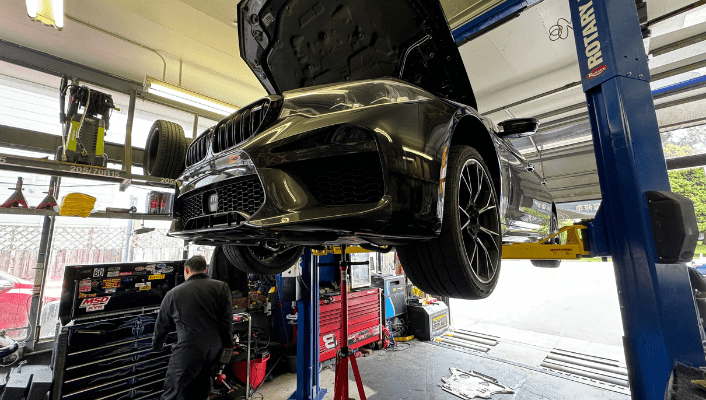 Car lifted for transmission and suspension repair at Masonic Smog & Repair.