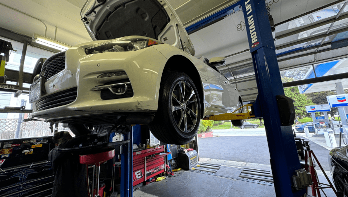 Car on lift during oil change at Masonic Smog & Repair shop.