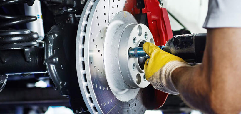 Technician replacing a vehicle brake rotor during maintenance.