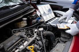 Technician diagnosing truck engine with laptop and diagnostic tools.