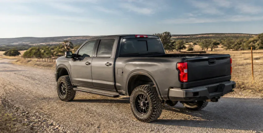 Gray heavy-duty pickup truck with off-road tires in a rural landscape.