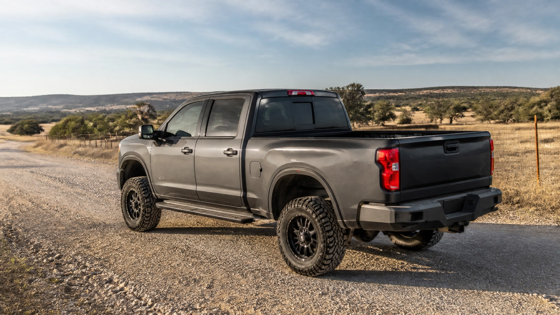 Gray heavy-duty pickup truck with off-road tires in a rural landscape.