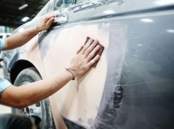 Skilled technician repairing a car's body with sanding tools.