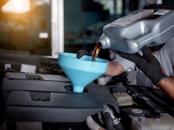 Engine oil being poured into a car engine during service.