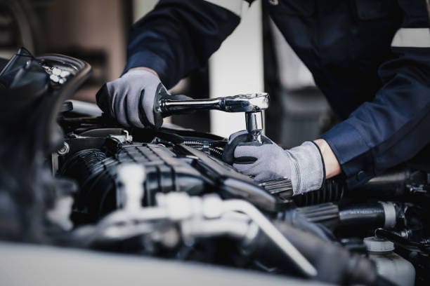 Engine repair technician inspecting car engine with tools.