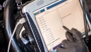 Vehicle diagnostic technician using a tablet for car repair services.