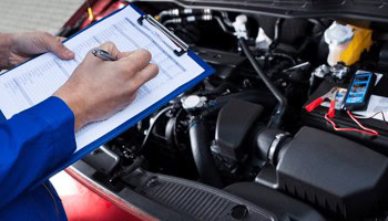 Automotive repair technician inspecting engine at Mécanique E.G.L. et fille Inc.