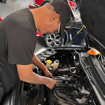Engine repair technician inspecting car engine at Meineke Car Care Center Fresno.