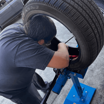 Technician inspecting a car tire on a blue lift at Meineke Fresno.