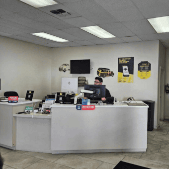 Friendly staff at Meineke Fresno reception desk with automotive service displays.