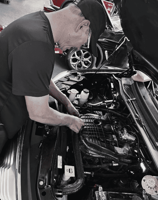 Auto mechanic inspecting engine at Meineke Car Care Center Fresno.