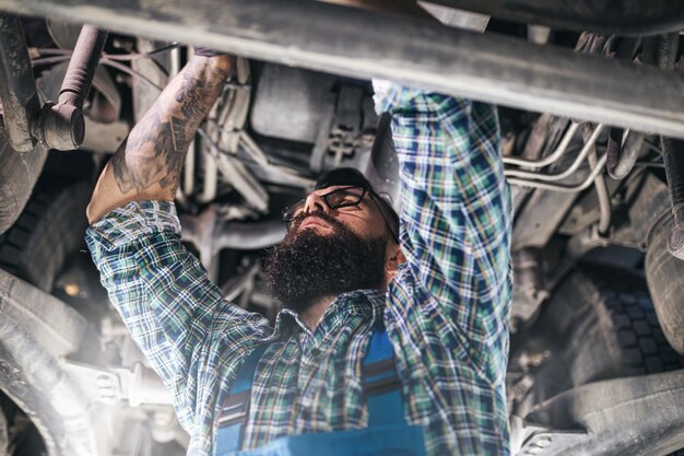 Auto mechanic inspecting car engine underneath for maintenance or repairs.