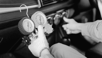 Technician performing engine diagnostics with pressure gauges in a car at Meineke Fresno.