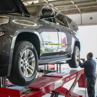 Technician inspecting a car on a hydraulic lift at Meineke Fresno.
