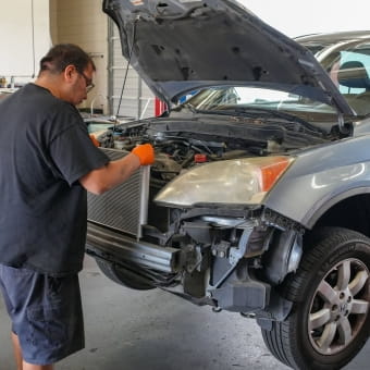 Technician inspecting a car engine at Meineke Car Care Center Fresno.