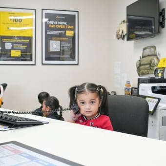 Young girl sitting at a desk in Meineke Car Care Center.