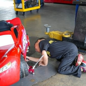 Technician repairing a red car in the Meineke Fresno workshop.