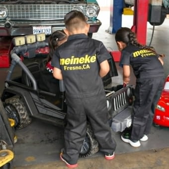 Kids working on a miniature car at Meineke Fresno, CA.