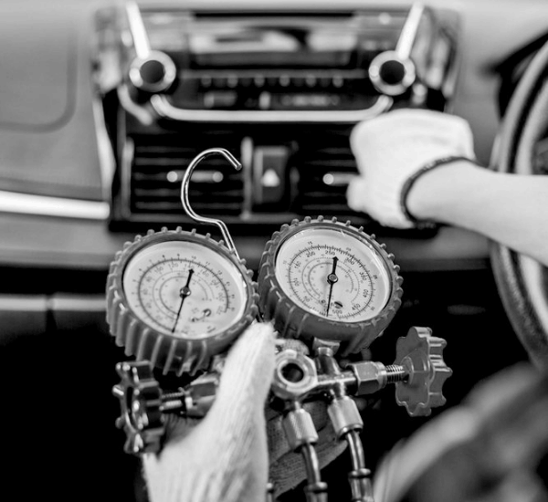 Technician checking refrigerant gauges during A/C repair at Meineke Fresno.