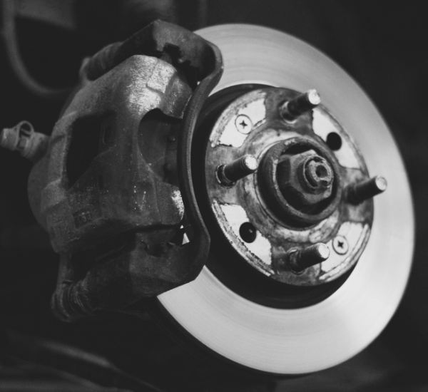 Close-up of a car brake caliper and disc brake in a repair shop.