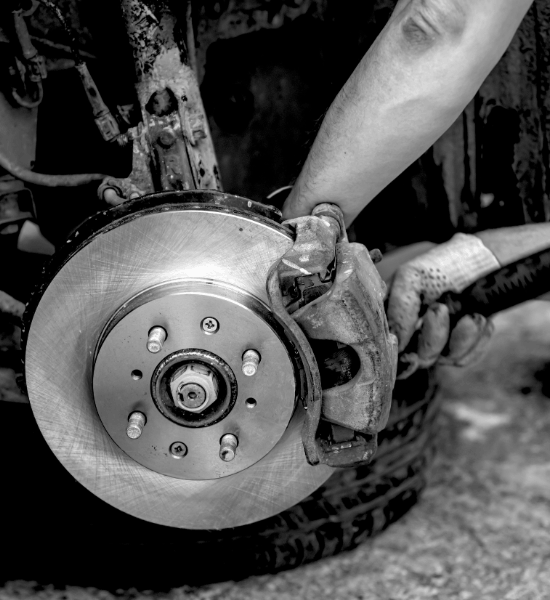 Technician inspecting a car's brake disc and caliper during brake service.