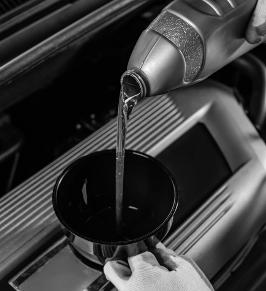 Technician pouring fresh engine oil into a car during an oil change.
