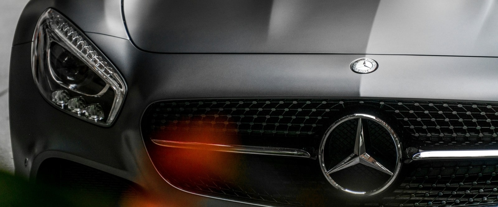 Close-up of a Mercedes-Benz front grille and emblem, showcasing luxury car design.
