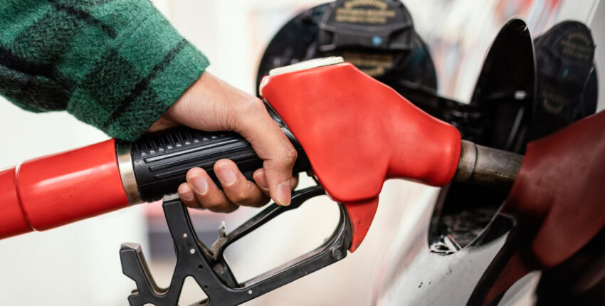 Close-up of a person refueling a car with a fuel nozzle at Mickey's Automotive, Inc.