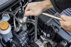 Mechanic inspecting engine components during repair at Mike's Automotive.