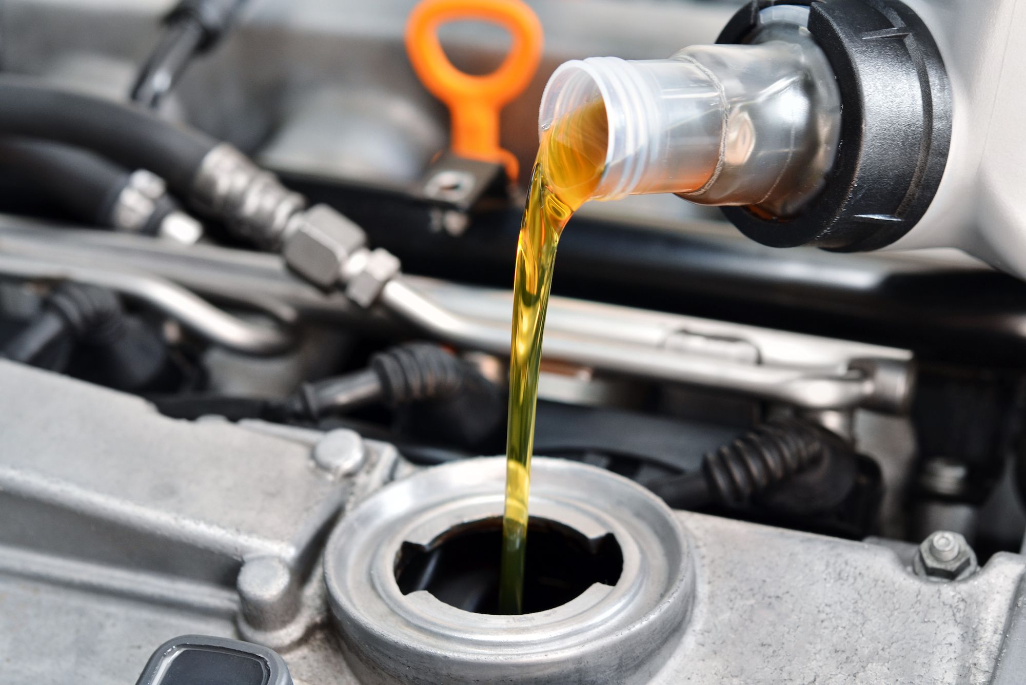 Automotive oil being poured into engine during oil change service.