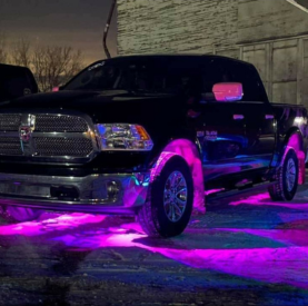 Custom black truck with vibrant pink and purple neon underglow lighting at night.