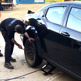 Technician changing a car tire at Minotaur Mechanical auto repair shop.