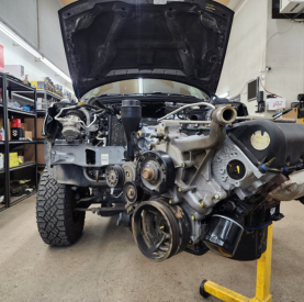 Vehicle engine being repaired with open hood at Minotaur Mechanical shop.