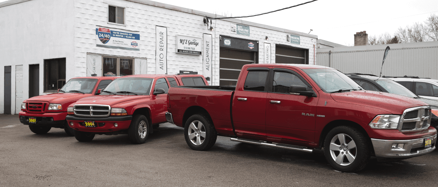 Used trucks and cars parked outside MJZ Garage auto sales in a commercial lot.