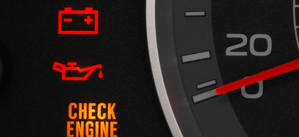 Car dashboard showing check engine and battery warning lights at MJZ Garage.
