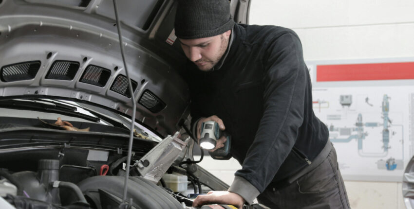 Skilled mechanic inspecting car engine at MJZ Garage auto repair shop.