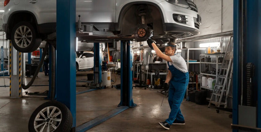 Skilled mechanic inspecting a car lifted on a hydraulic lift at MJZ Garage.