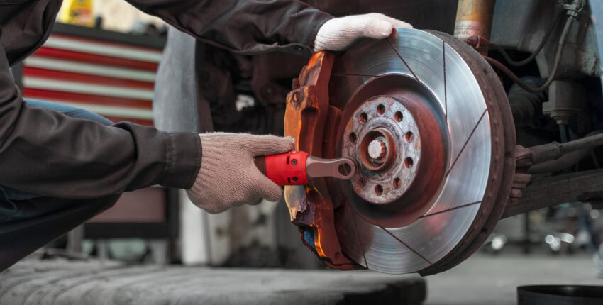 Mechanic replacing a car brake disc with a wrench at MJZ Garage.
