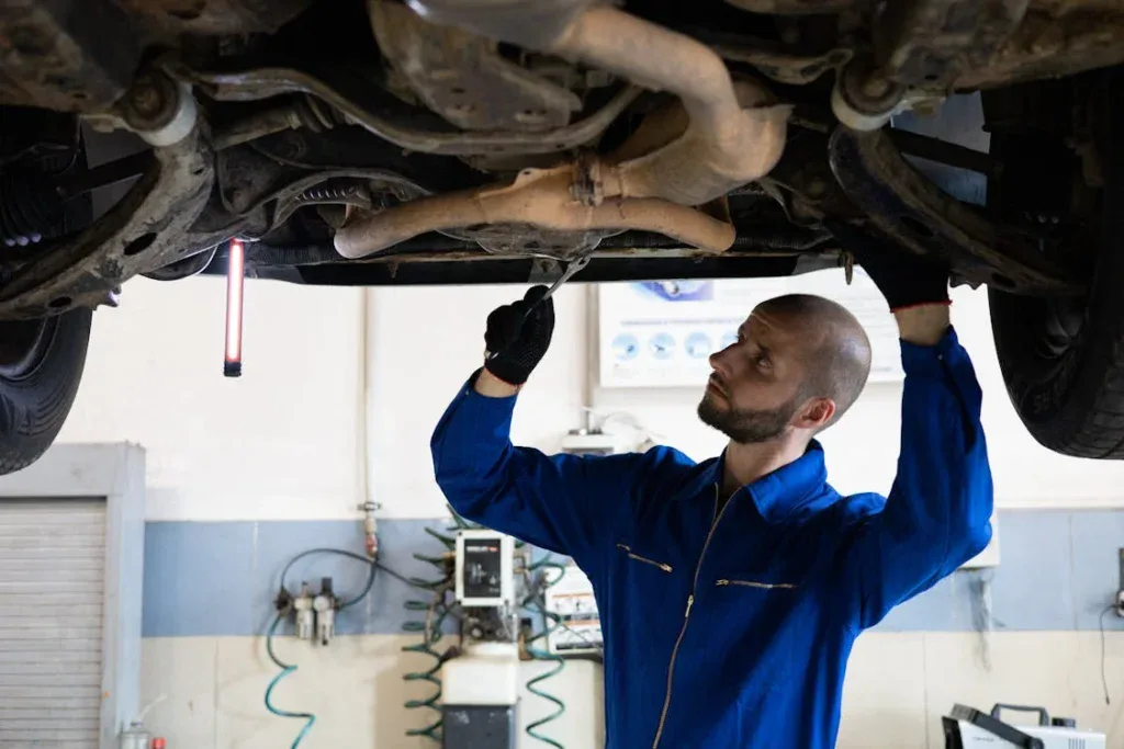 Auto mechanic inspecting vehicle underside for safety and maintenance.