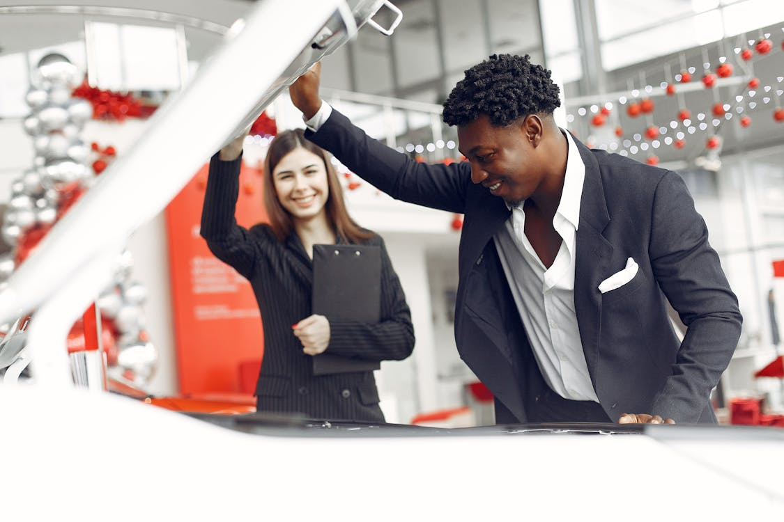 Auto repair technician inspecting a car engine at a service center.