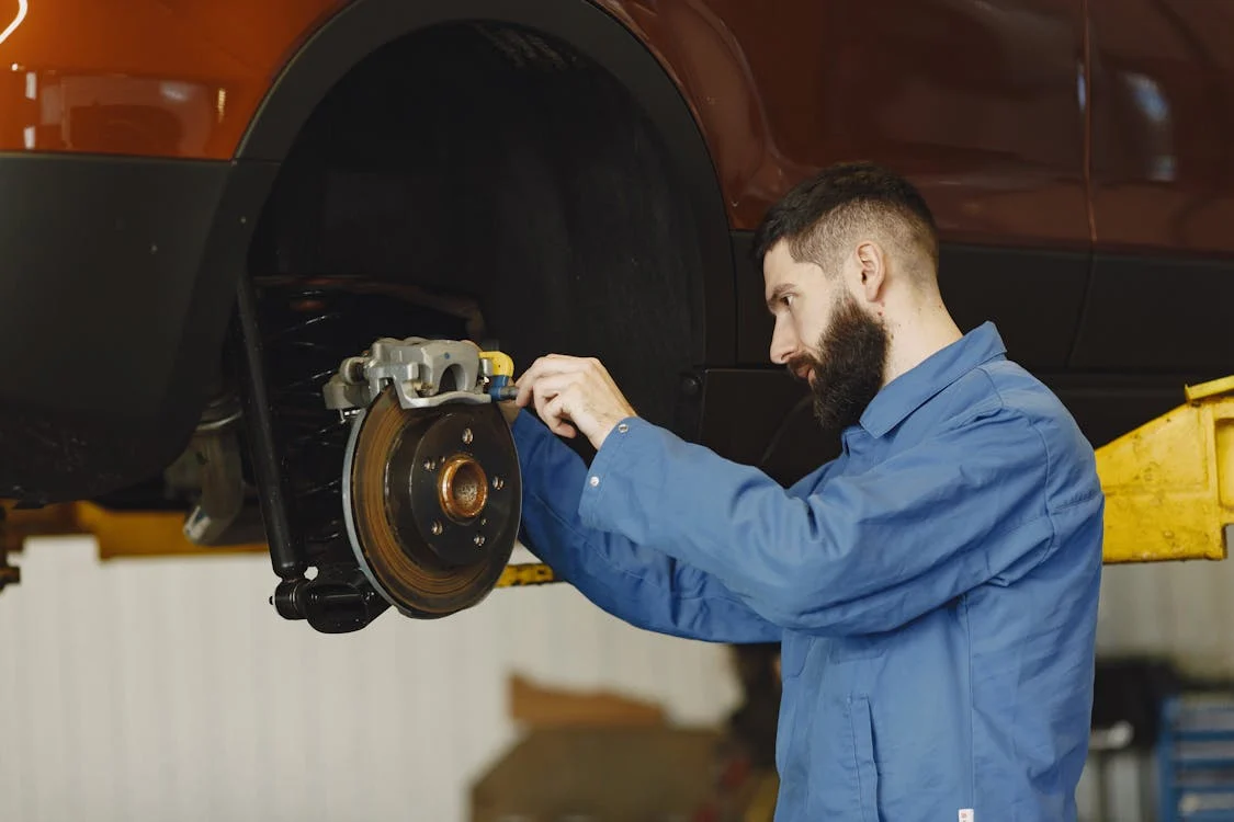 Auto mechanic inspecting brake system on a car's wheel.