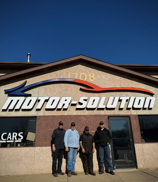 Exterior view of Motor Solution auto repair shop with staff members.