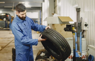 Technician inspecting a car tire at Motor Solution workshop.