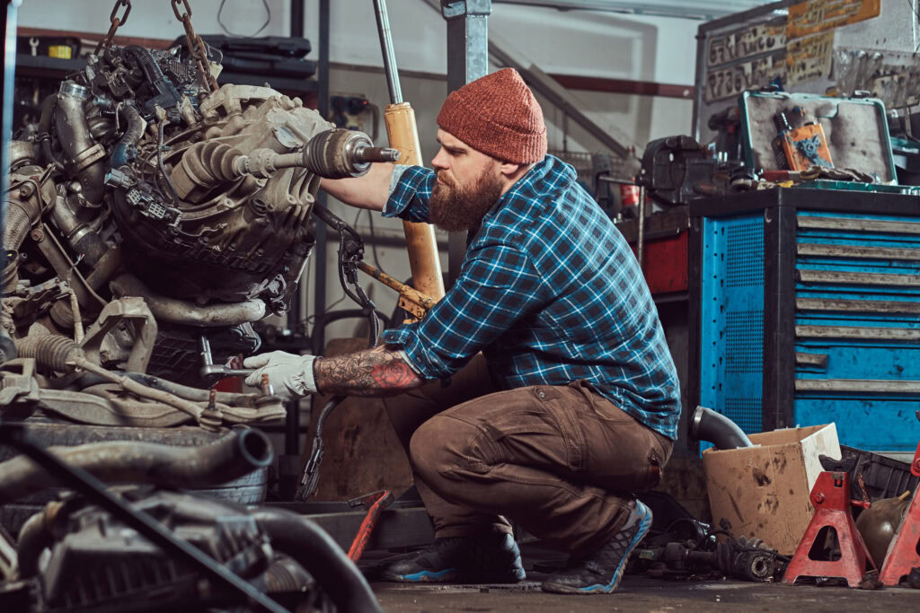 Engine diagnostics technician working on a vehicle engine in a repair shop.