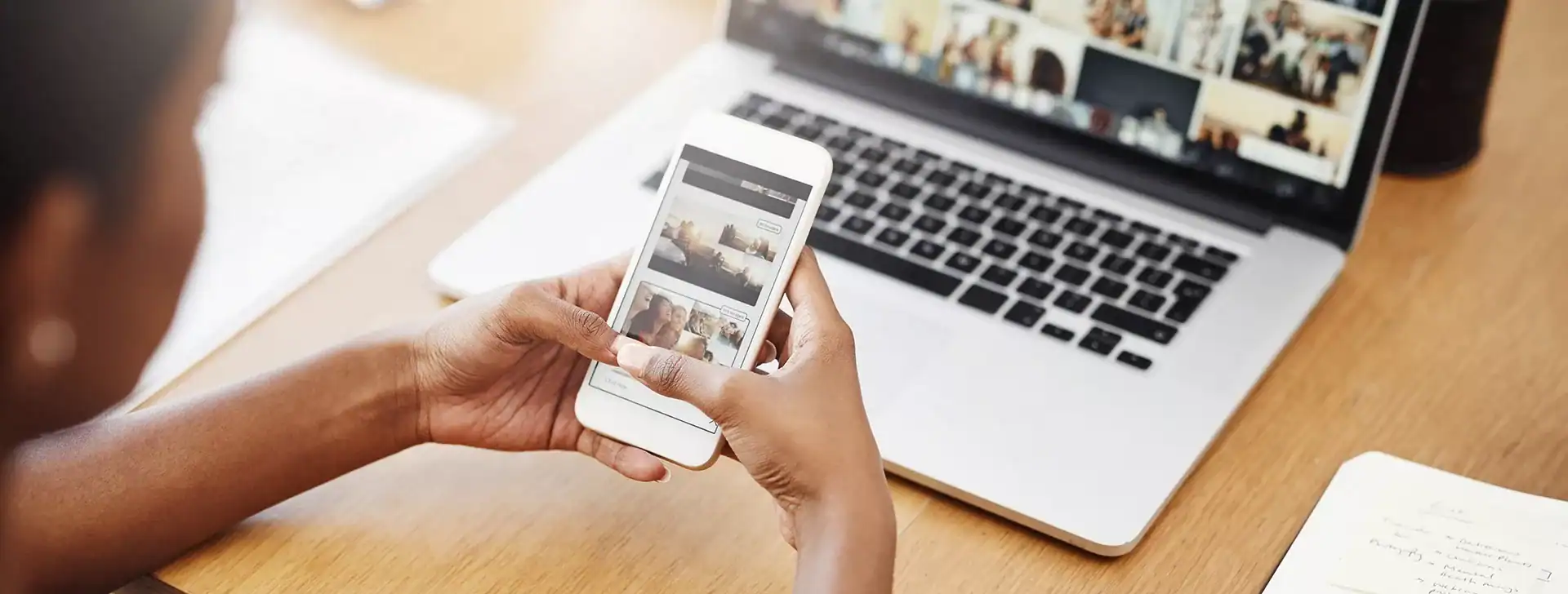 Mobile device showing social media posts with laptop and notes in the background.
