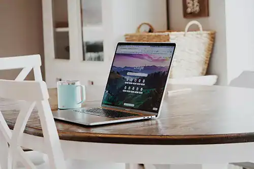 Laptop on a dining table displaying a scenic digital landscape, representing digital marketing solutions by Moxie360 Marketing.