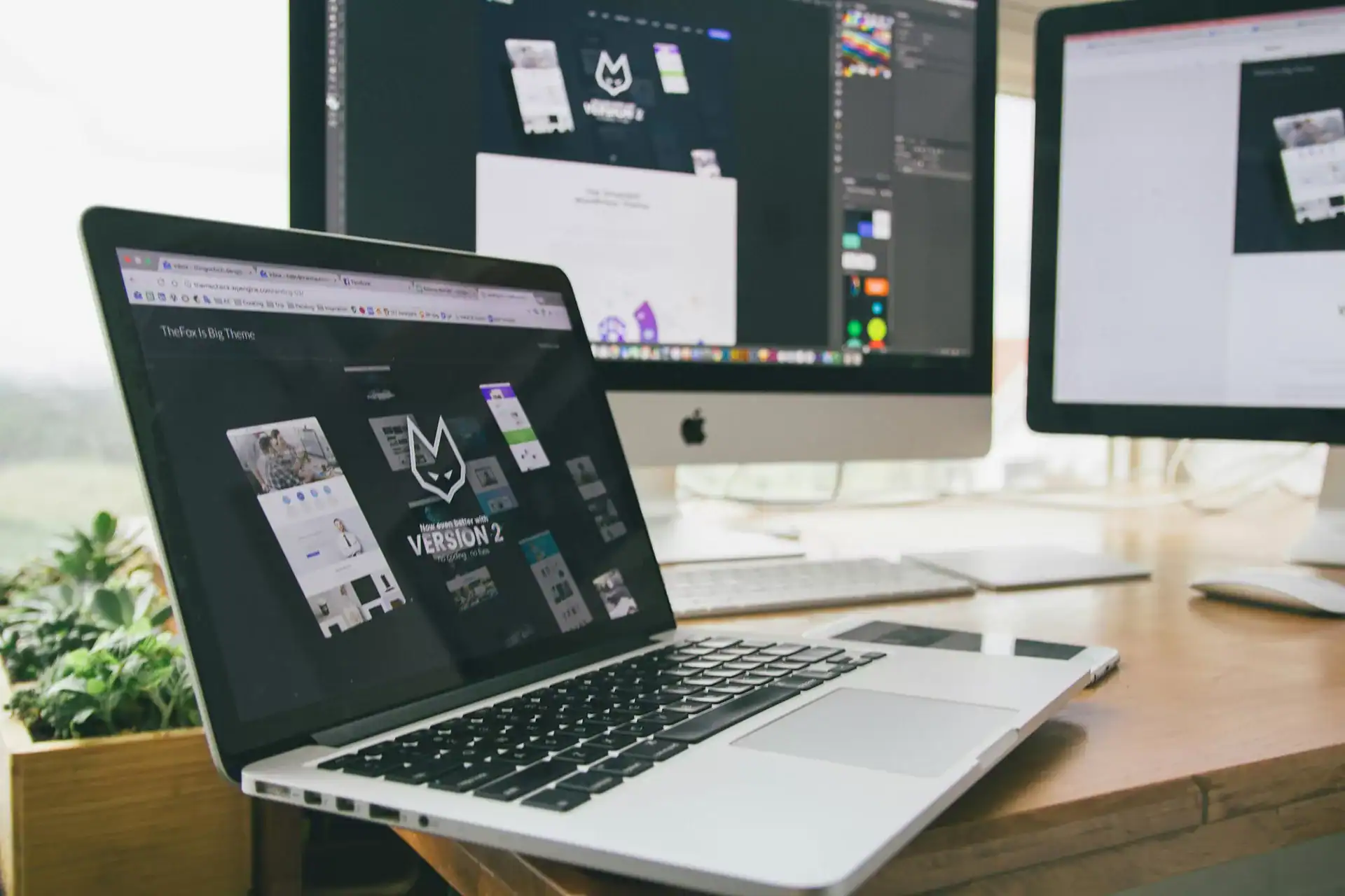 Creative graphic design work for marketing on multiple computer screens, showcasing digital marketing and branding.