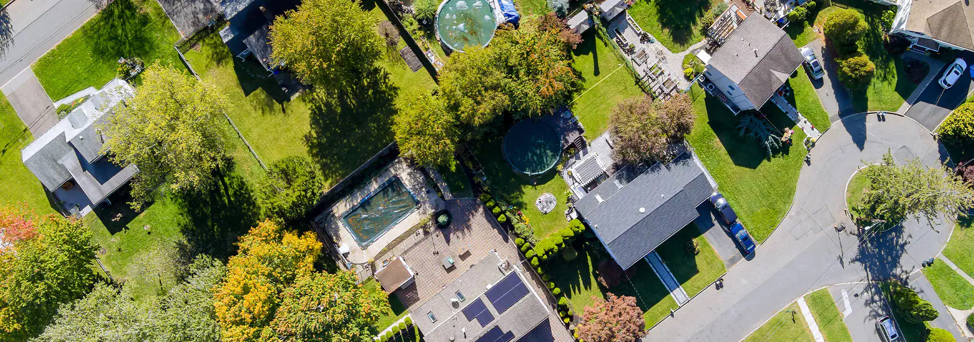 Aerial view of suburban neighborhood with greenery, houses, and a roundabout, showcasing residential community.