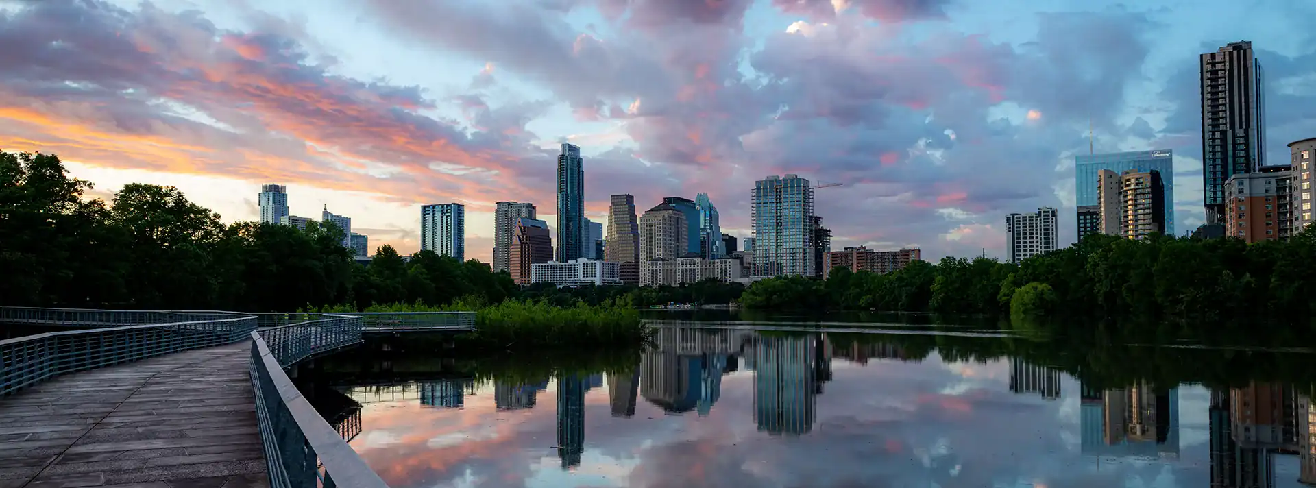 Vibrant Austin skyline at sunset with modern skyscrapers and lush greenery reflecting on Lady Bird Lake.