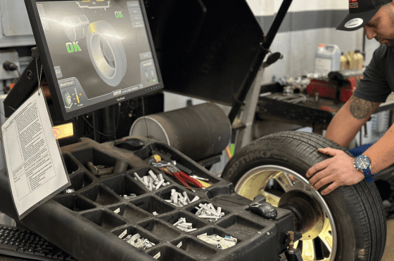 Technician inspecting car tire with advanced diagnostic tools.